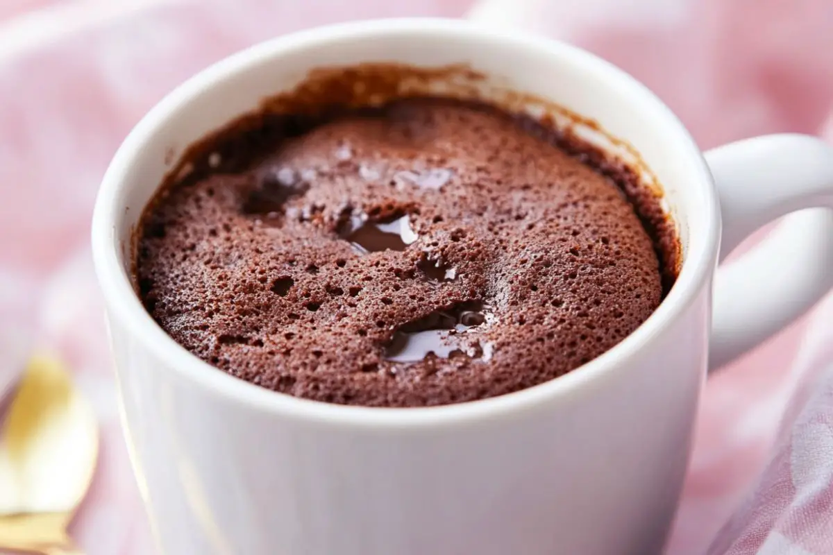 A fluffy chocolate mug cake in a white mug, highlighting the perfect texture of a microwave-baked dessert.