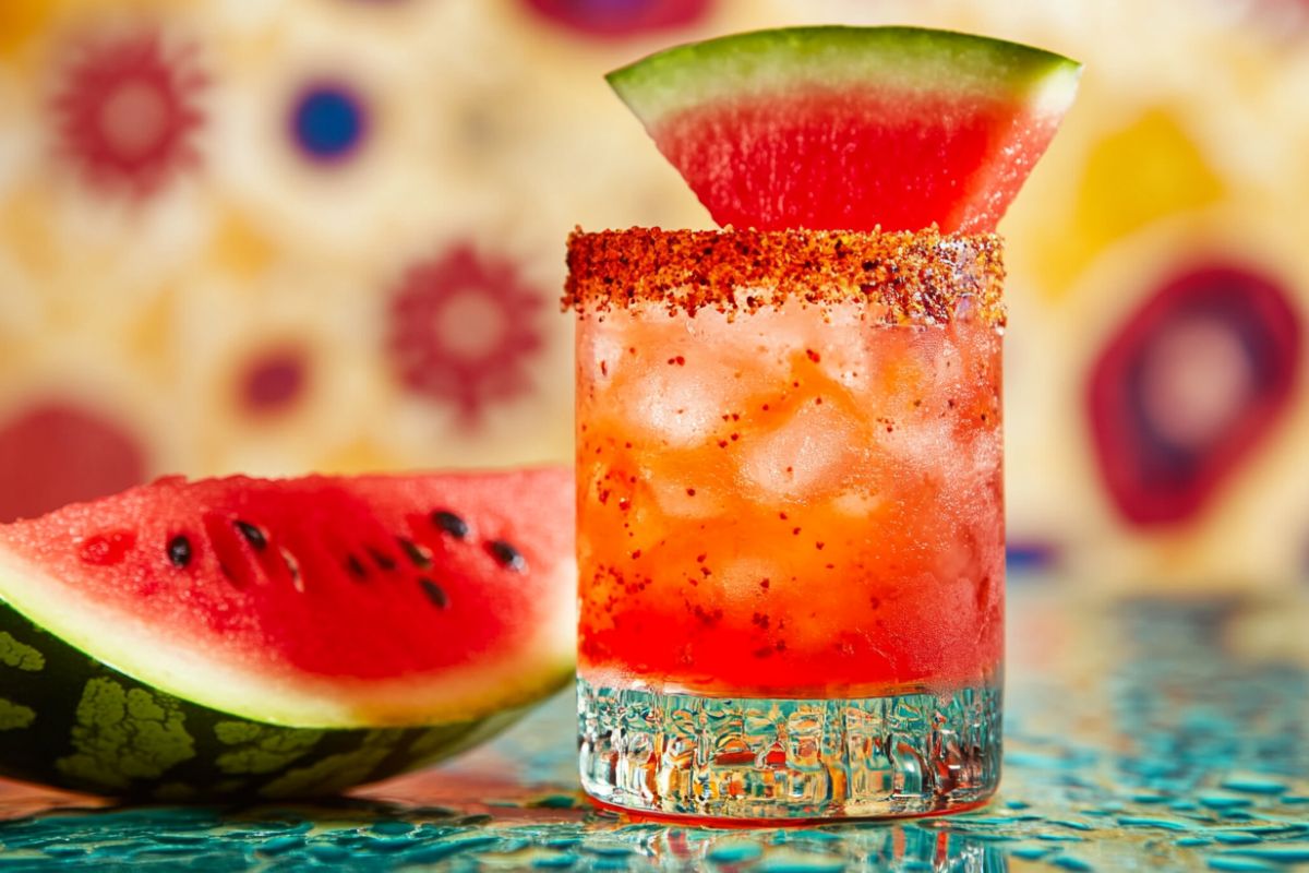 Colorful Mexican candy shot with a Tajín rim and watermelon garnish